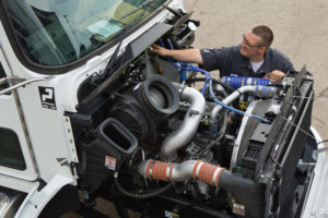 A skilled mobile car mechanic is engaged in repairing a truck engine, demonstrating professionalism and technical proficiency.