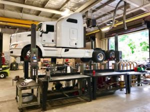 A semi truck on a lift in a garage, highlighting the diesel truck repair process being conducted.