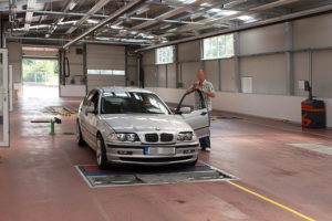 In a garage, a man examines a car, focusing on vehicle inspection and maintenance for optimal performance.