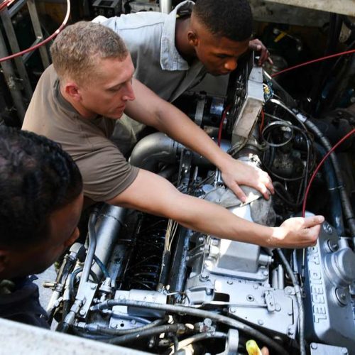 Two men collaborating on diesel engine maintenance, concentrating on repairs to improve the vehicle's operational efficiency.