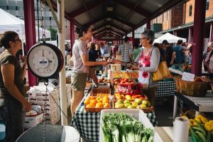 hoppers explore a lively outdoor farmers market in Felton, California, selecting fresh fruits, vegetables, and artisanal products.