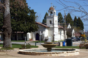 A serene fountain in front of a church, surrounded by lush greenery in Soquel, California, showcasing tranquil beauty.