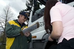 A man and woman are positioned next to a truck, performing a vehicle inspection to assess its condition and safety.