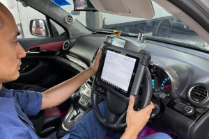 A man engaged with a tablet in a car, emphasizing the need for vehicle inspection and responsible driving behavior.