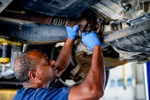 A technician in blue gloves performs routine service and maintenance on a vehicle, ensuring optimal performance and safety.