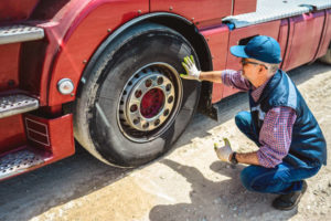 A technician is fixing a truck tire as part of a commercial vehicle inspection, highlighting maintenance and safety measures.