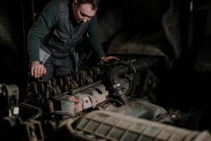 A mechanic inspects and repairs the engine of a diesel truck, dedicated to restoring the vehicle's operational capabilities.